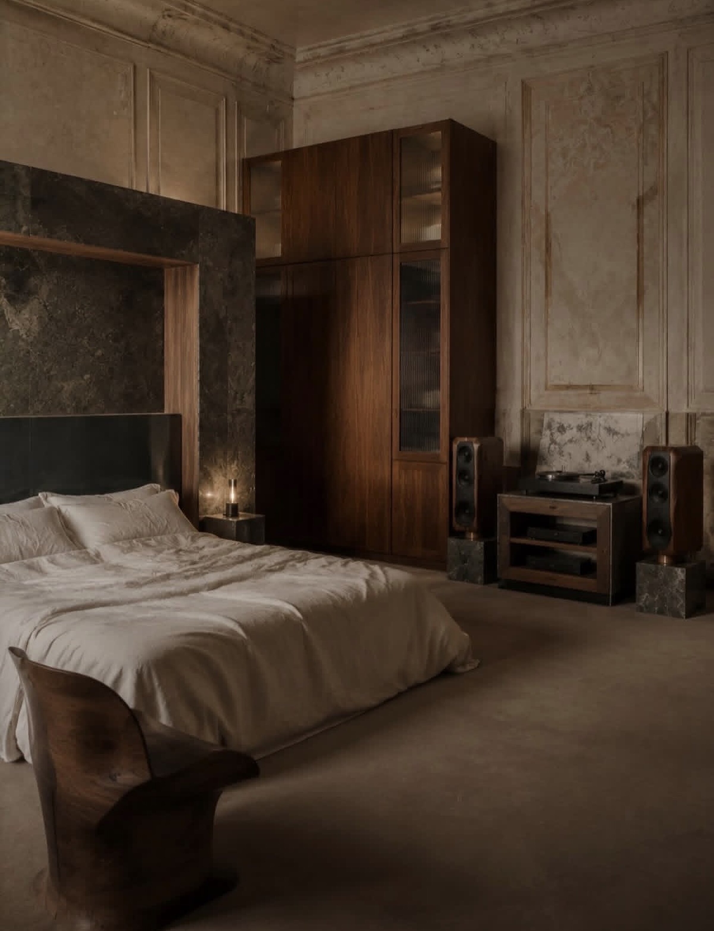 Bedroom with aged plaster panelling, a dark stone headboard wall, walnut wardrobe and a turntable between speakers on marble plinths